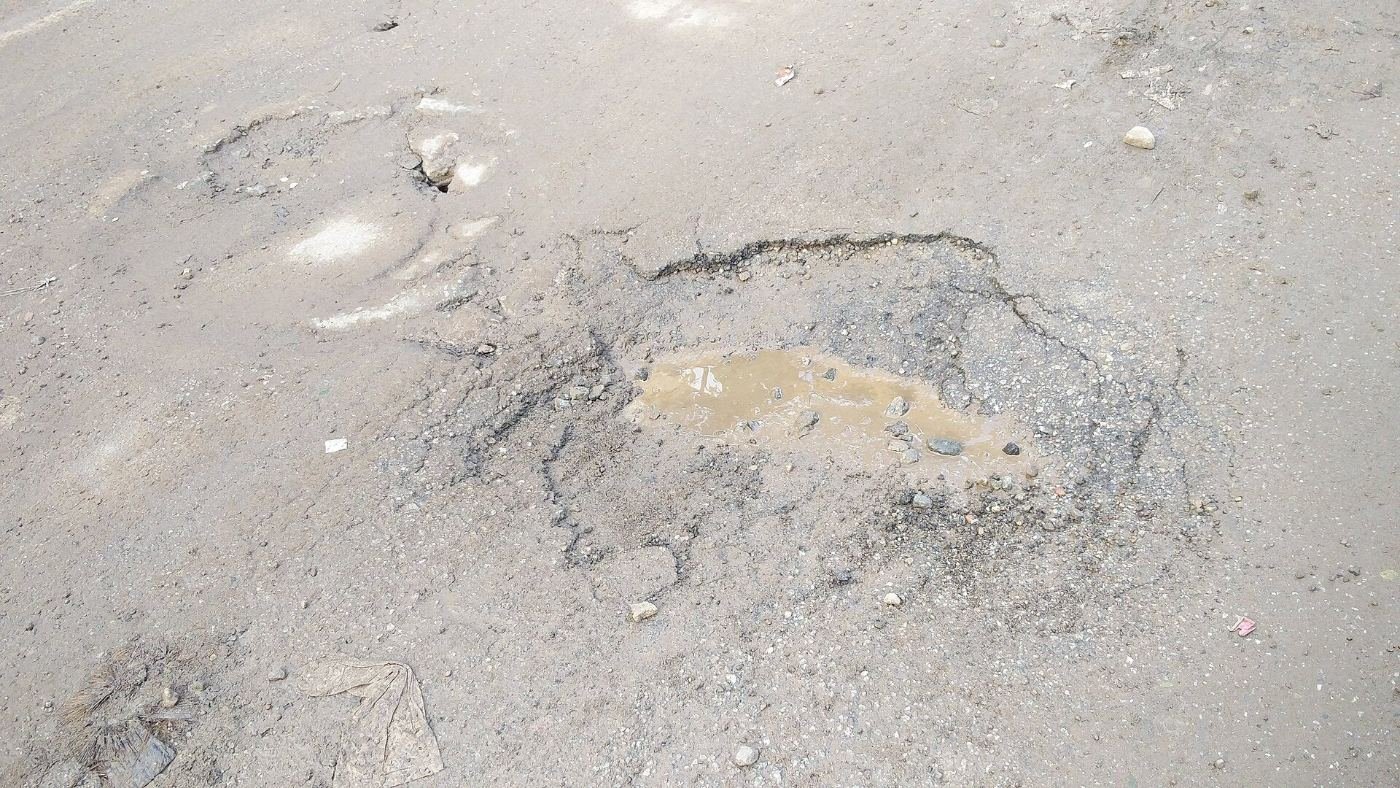 A deformed and waterlogged stretch of asphalt on a Bengaluru city road